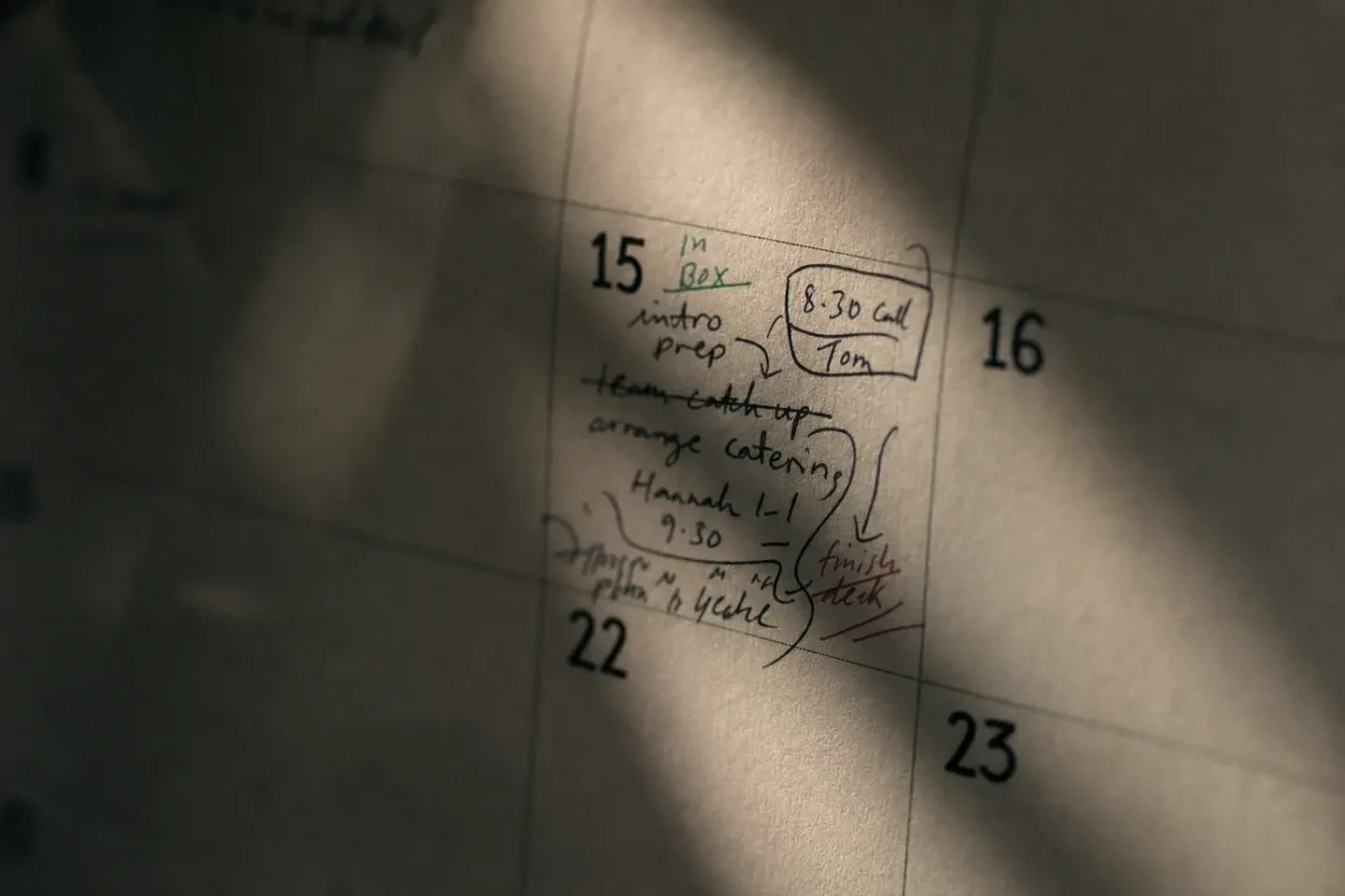 A wall planner in low morning light with several days left completely blank and one day densely annotated, shot close enough to read the paper texture